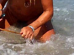 Moden kvinde med strakte piercinger i brystvorten og flere fissepiercinger på stranden