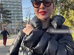 A stunning woman exposes her large breasts while strolling in a park