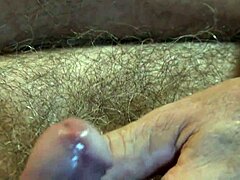 Zrel moški dobi dobro masažo svojega penisa, ki je prekrit s semenom